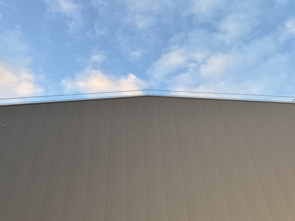 Attika und Wandfläche aus Sandwichpaneelen vor blauem Himmel