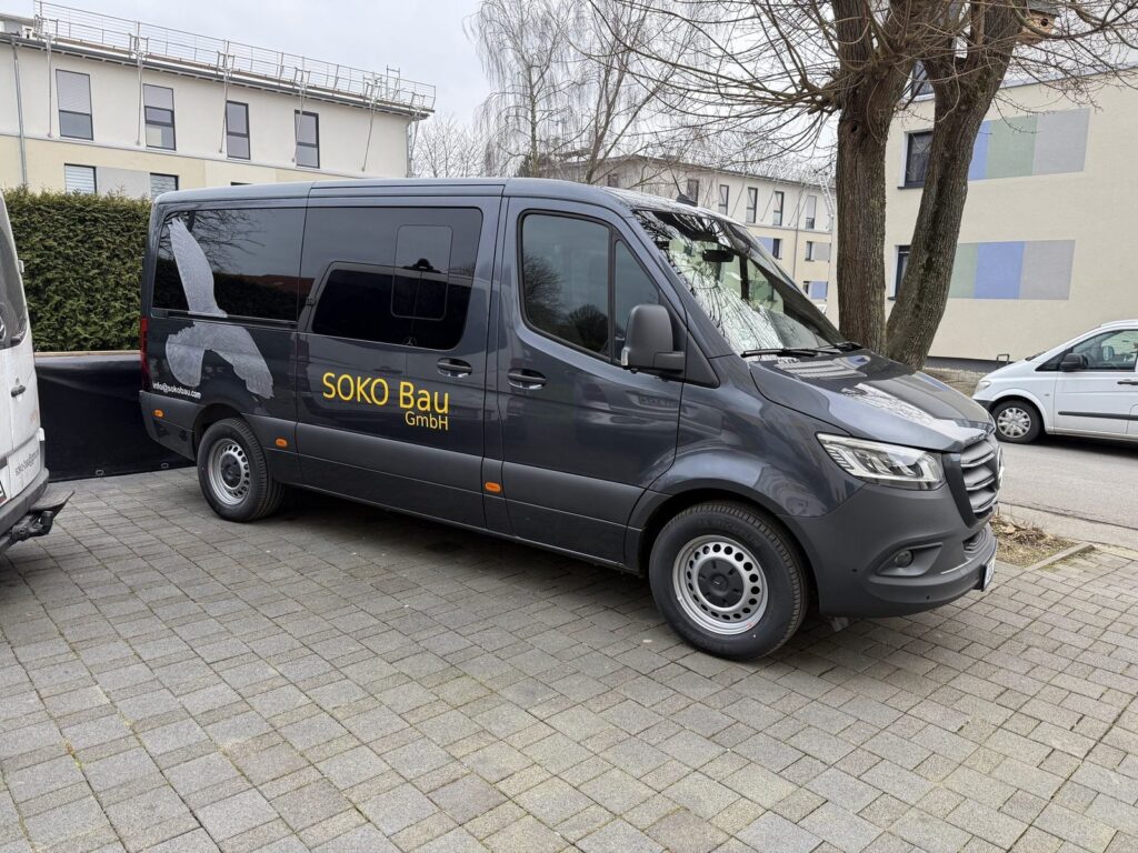 Anthrazitfarbener Soko-Bau-Transporter mit Falke und Firmenschriftzug